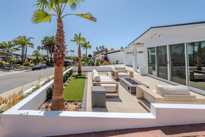 The raised front terrace with built in seating and a fire feature, palms and the street beyond.