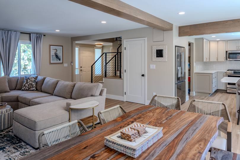 Finished open living and dining space at Escalones with exposed ceiling beams, a live edge table and wide plank floors.