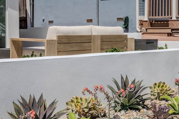 Close view of agave and succulent planting in gravel against white stucco.
