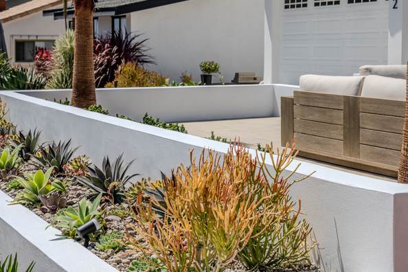 Terraced white stucco planter wall stepping down toward the garage and driveway.