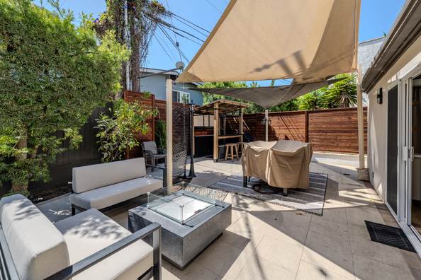 Outdoor lounge under a shade sail with a fire table and built in seating.