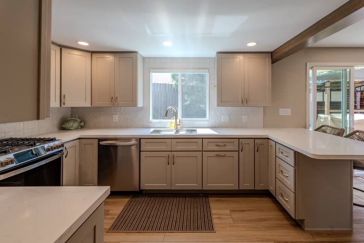 A finished kitchen with pale cabinetry, quartz counters and a window over the sink.