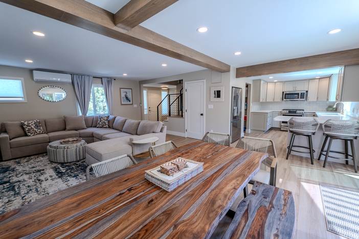 Open living and dining space with exposed ceiling beams and a live edge table.
