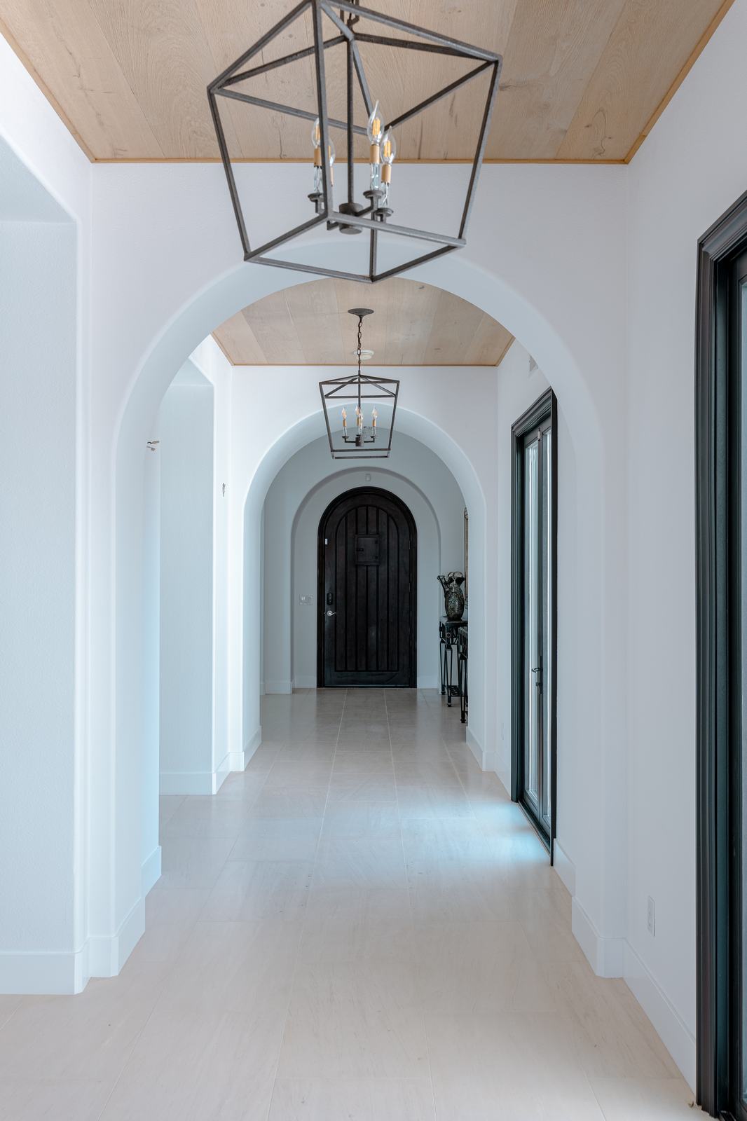 Arched entry hall with a lantern pendant and a solid entry door