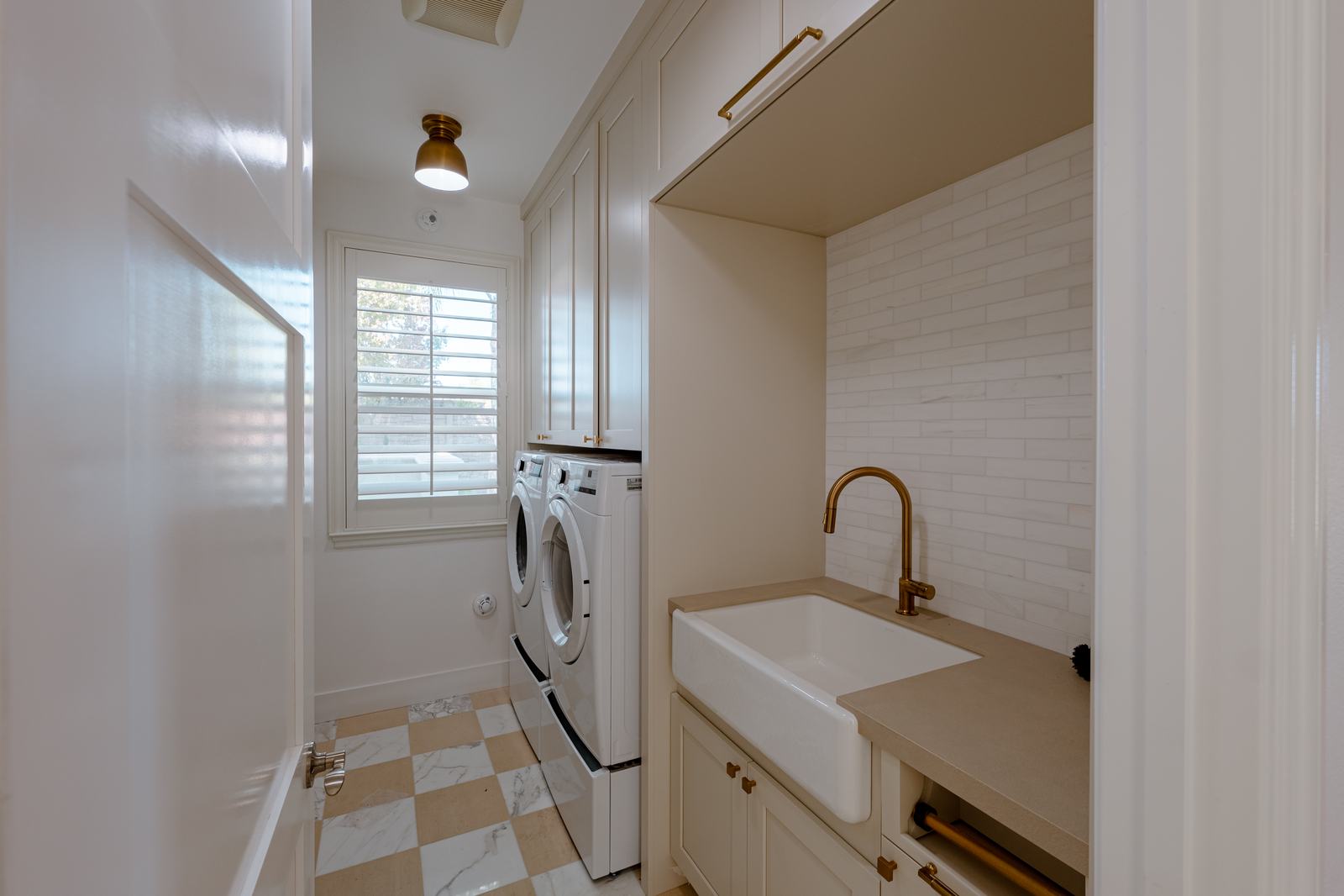 Laundry room with an apron sink, brass faucet and a checkerboard floor