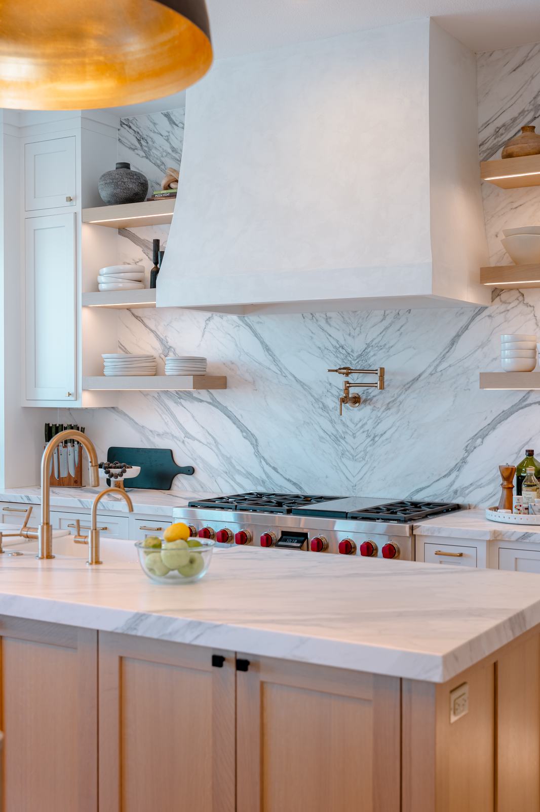 Kitchen range wall with a stone slab backsplash and a brass pot filler