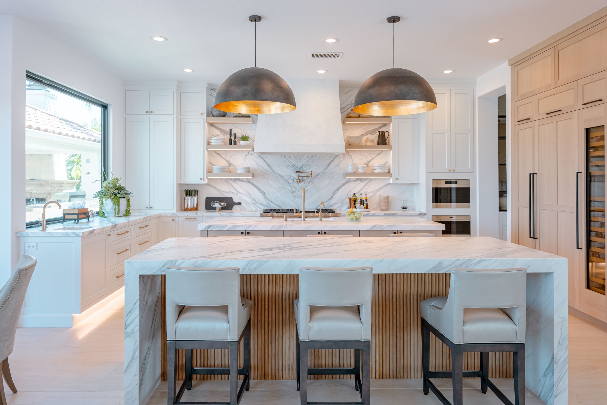 Finished custom kitchen with a marble island, white oak cabinetry and paired dome pendants