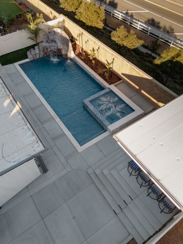 Aerial view of a pool with rock grotto slide and automatic cover