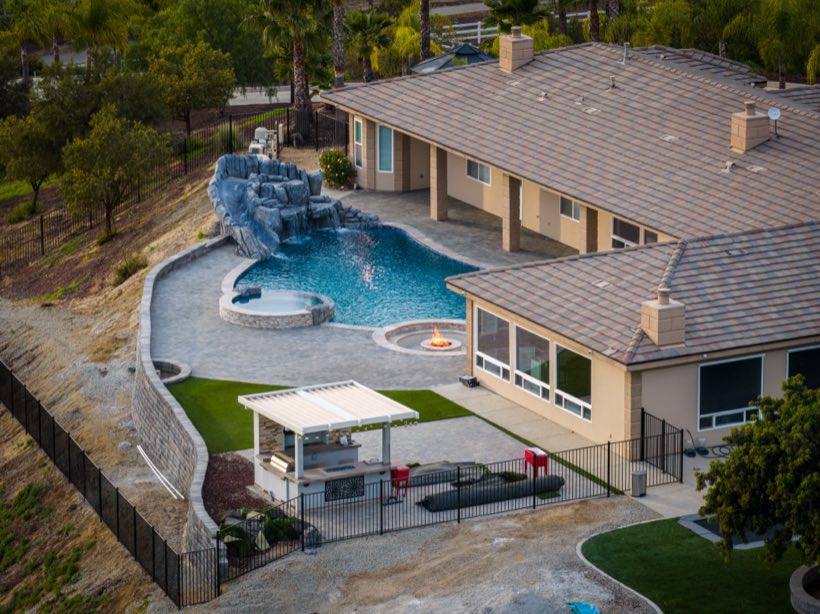Dusk aerial of an estate backyard with freeform pool, spa and fire pit