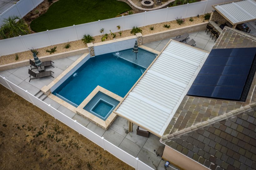 Aerial view of a pool and raised spa with white patio cover