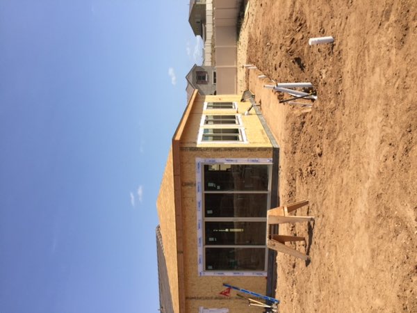 The addition sheathed in OSB with a wide slider and a row of windows fitted, roof decked.