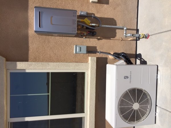 Exterior wall with a tankless water heater, condenser unit and electrical sub panel installed.
