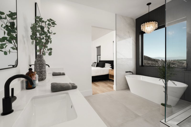 A finished bathroom with a freestanding tub, large format stone and a glass shower.