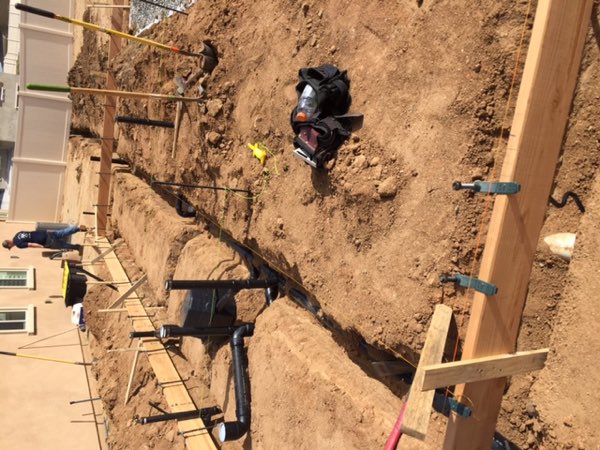 Open trenches with black underground drain lines run and rebar set, ready for inspection.