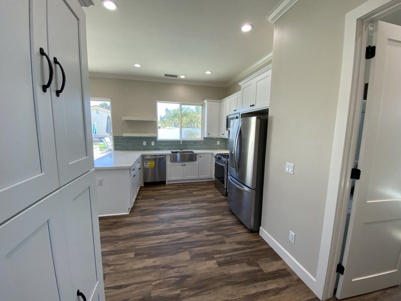 The finished kitchen inside an ADU with an island, white cabinets and full appliances.
