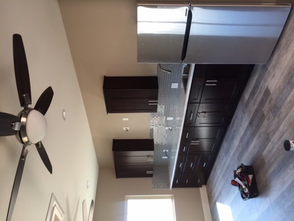 Finished kitchen inside the addition with dark cabinets, stone counters and appliances in place.